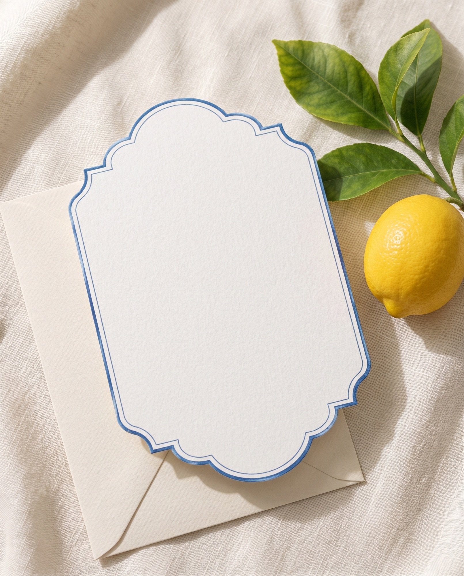 A lemon-bordered invitation on cream linen with a lemon and its leaves